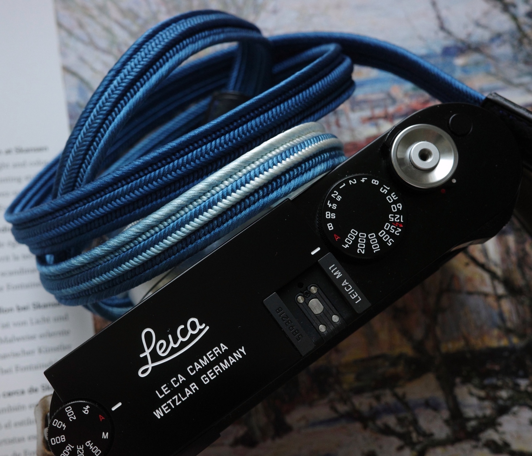 Close up of HOZUMA Blue Mt. Fuji Kumihimo silk camera strap showing braided texture, attached to a black Leica M11 camera.